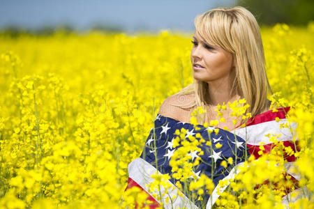 一个黄色田野上挂着美国国旗的漂亮女孩