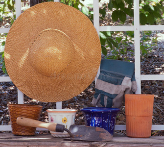 带庭院盆和工具的棚架上的草帽图片