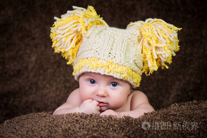 新生儿在针织的冬帽米色背景上
