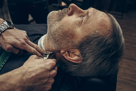 特写侧面后视图英俊的高级大胡子白种人得到胡子梳理现代理发店