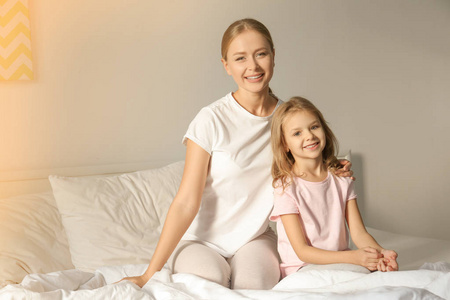 快乐的母亲和她的女儿在床上儿童房