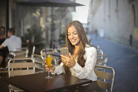 女孩与智能手机在一个户外酒吧