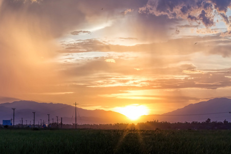 阴云密布的天空橙色夕阳，绿色的田野