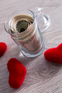 钱和红色的心。美元在打开罐子上木制的灰色背景。复制空间。爱。情人节