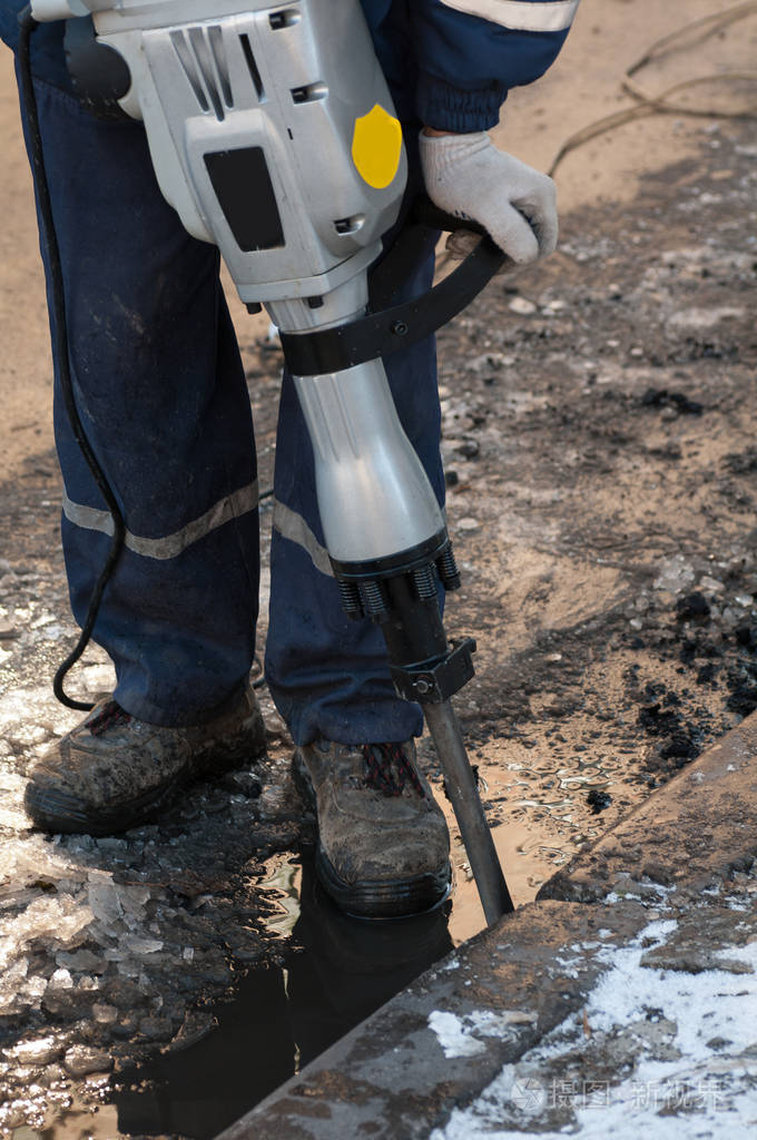 在城市的街道上工作的电钻的男人