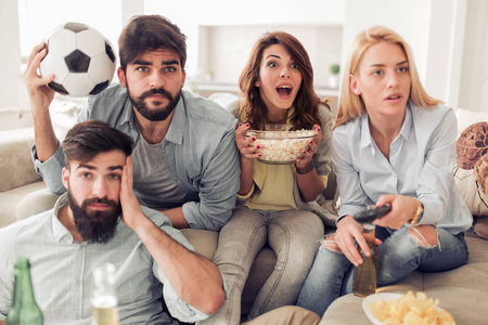 快乐的一群朋友在电视上看足球比赛, 在家玩得很开心。