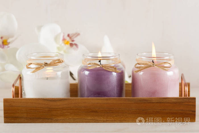 木托盘上的白色, 紫色和粉红色的蜡烛