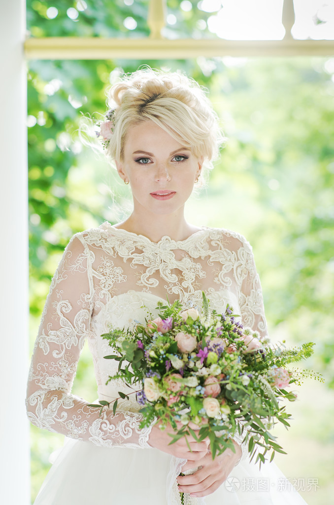 美丽的金发新娘在婚礼花束豪华装