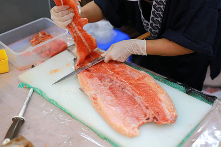 日本厨师为鲑鱼寿司切片生鱼片。厨师在切板上准备新鲜鲑鱼