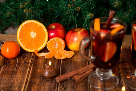 圣诞葡萄酒的水果和香料木制的桌子上。圣诞装饰品在背景中。冬季暖饮料水果周围的成分