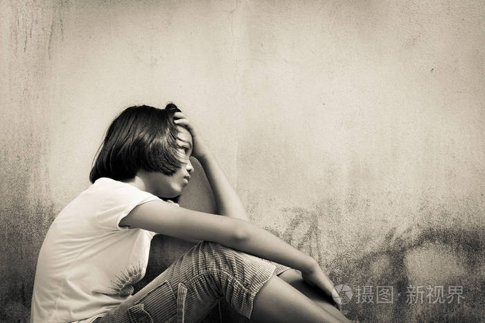 亚洲女孩伤心独自一人坐在白色熊老墙附近