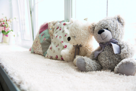 两只泰迪熊和光的窗台上放着两个枕头