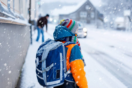 快乐的孩子男孩玩雪在去学校的路上