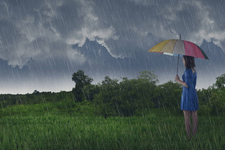 在田野下雨时用雨伞的漂亮亚洲女人图片