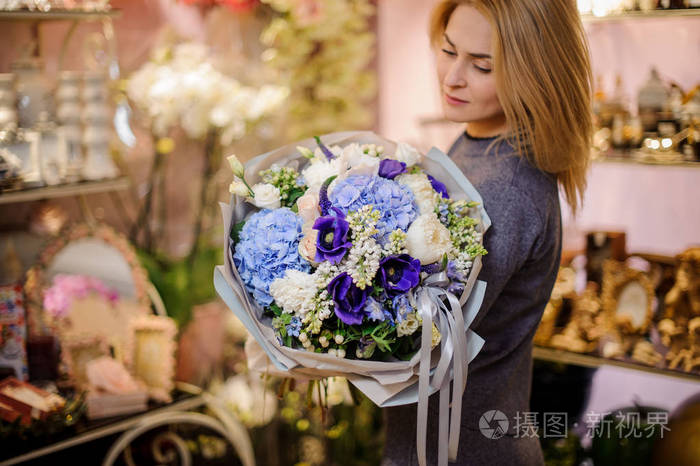 美丽的女孩捧着一束白色, 蓝色和紫罗兰色的花朵