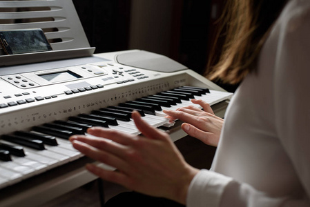 穿白衬衣的女孩在用你的智能手机上的应用软件演奏电子钢琴。