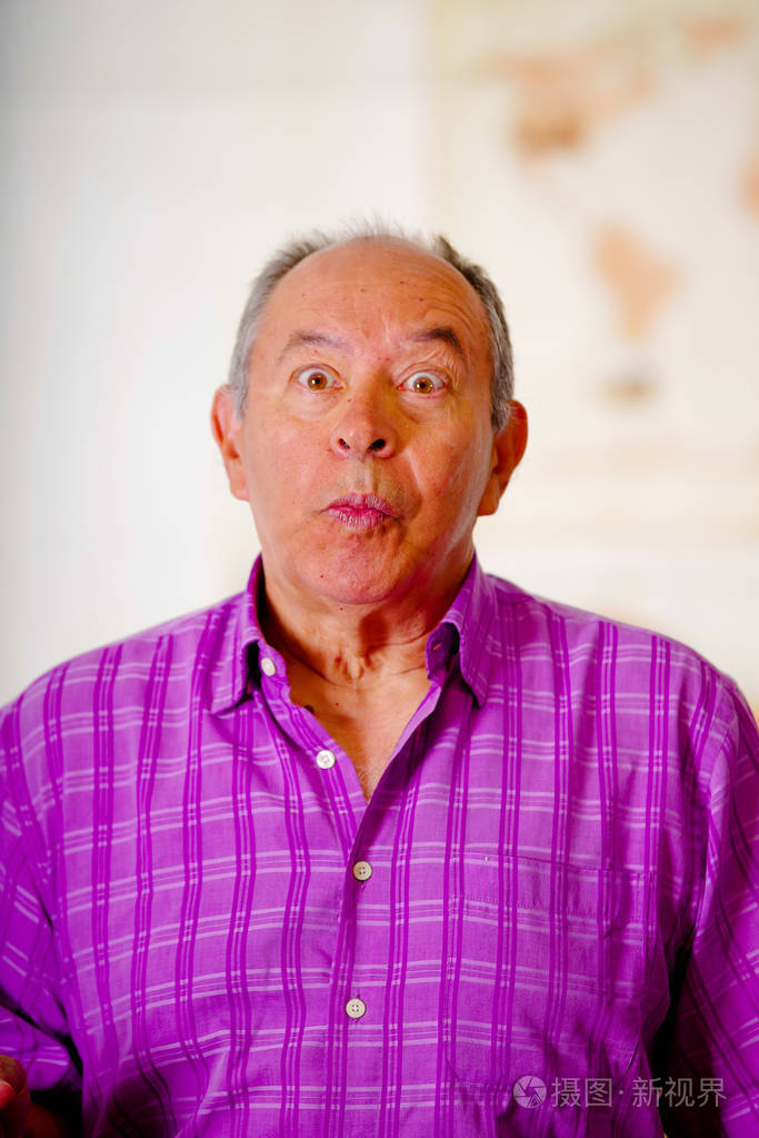 画像一个suprissed的老头做一个滑稽的脸穿着紫色的方形t恤在一个模糊