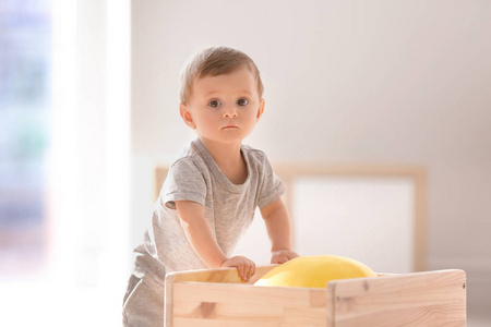 可爱的婴儿抱着木车在室内。学习走路