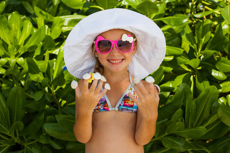 太阳镜和帽子拿手指着壳上的漂亮微笑女孩。节日概念