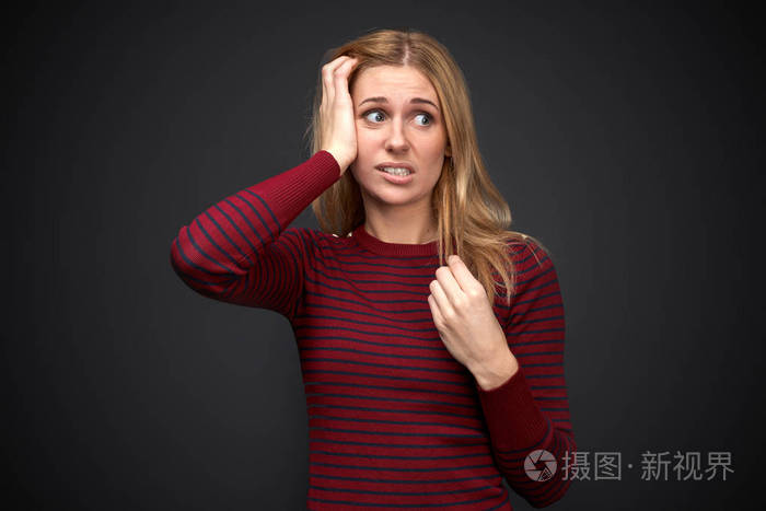 工作室肖像一个美丽的年轻的金发女郎令人不安的心烦震惊的表情在她的