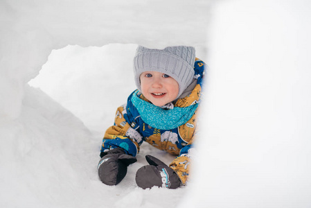 可爱的小男孩孩子在外面玩，他在堆雪挖在冬天里的雪屋堡隧道