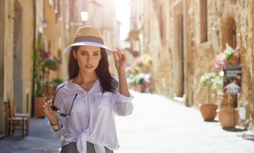 有魅力的女人戴着帽子在古老的意大利小镇旅游