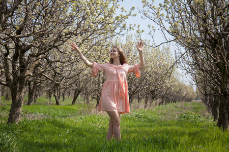 粉红色礼服的金发女郎走在春天盛开的花园里