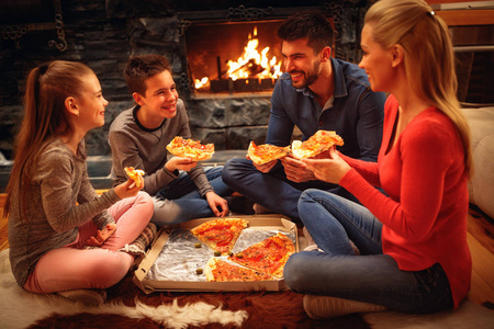 微笑的父母和孩子有乐趣和吃比萨