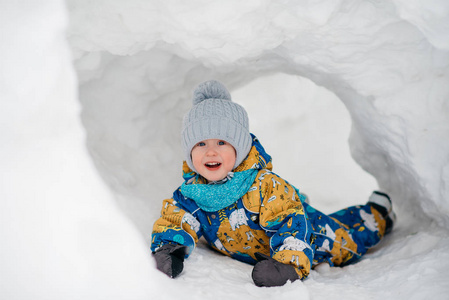 可爱的小男孩孩子在外面玩，他在堆雪挖在冬天里的雪屋堡隧道