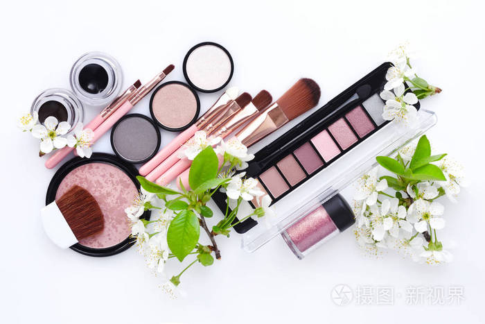 化妆刷和装饰化妆品与盛开的树枝在白色背景