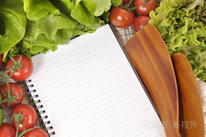 用空白食谱书或购物单和木制汤匙选择沙拉蔬菜