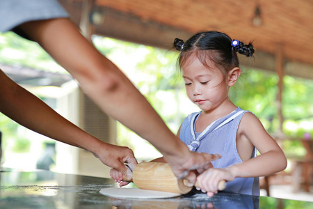 母亲和可爱的小女孩，用木滚针在面团上比萨饼。自制过程中制备比萨饼