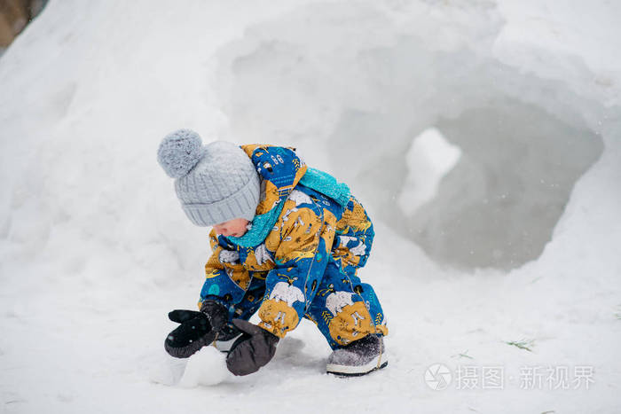 可爱的小男孩孩子在外面玩他在堆雪挖在冬天里的雪屋堡隧道