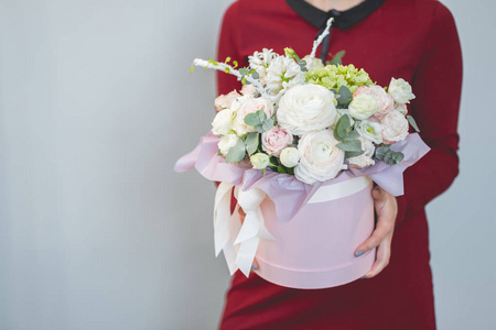 手持粉红色礼品盒的女性手捧鲜花