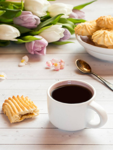 木桌上有饼干和郁金香的咖啡杯