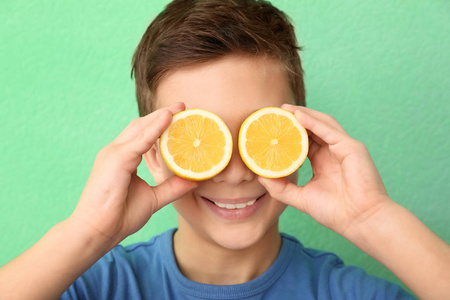 有趣的小男孩与柑橘果在颜色背景