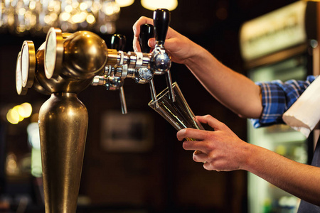 酒保倒的鲜啤酒在酒吧，酒保手在浇注吃水的啤酒，啤酒从水龙头 玻璃装满啤酒 鲜啤酒 酒吧的啤酒。Bar.Restaurant