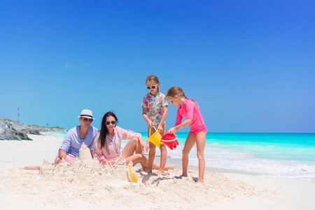 四家庭在热带白色海滩做沙子城堡
