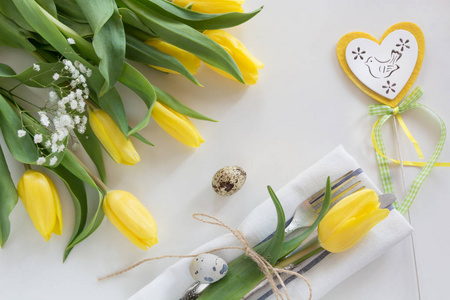复活节概念与副本空间为你快乐的复活节祝福。与黄色的郁金香，在白色背景上的鹌鹑蛋装饰复活节的地方设置