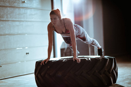 crossfit 训练的年轻肌肉妇女在轮胎上做俯卧撑锻炼