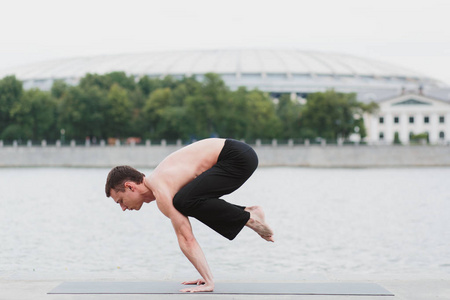 练习瑜伽体式中城市滨水区的一名年轻男子