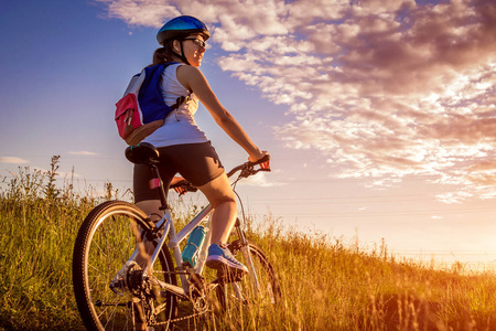 年轻的自行车骑在夏天的田野。健康的生活方式概念