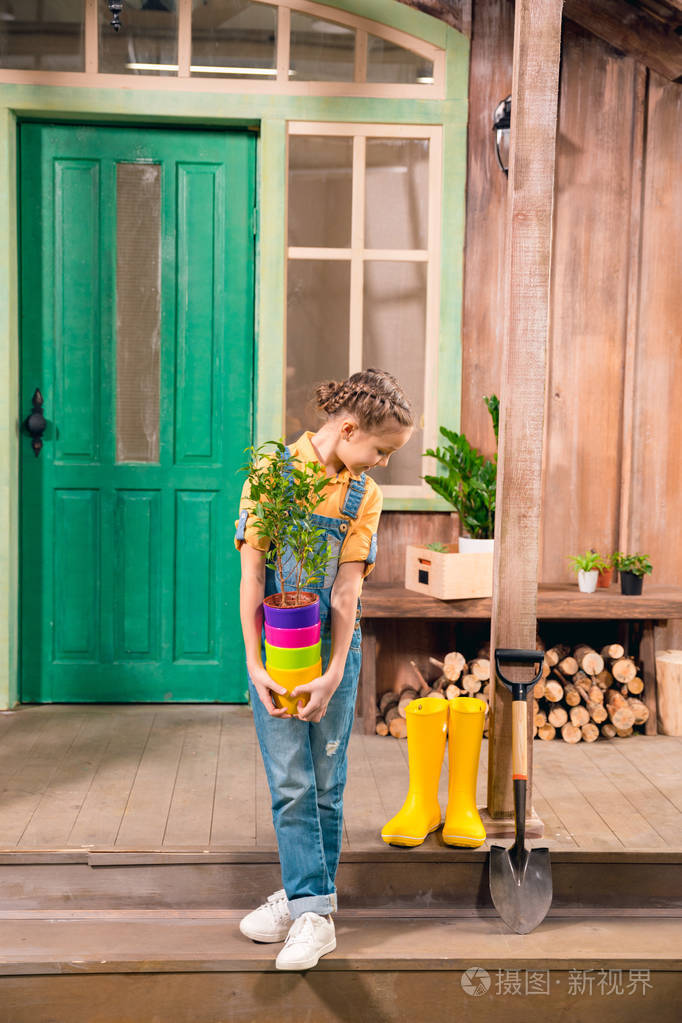 可爱的小女孩抱着多彩花盆与家居植物俯视