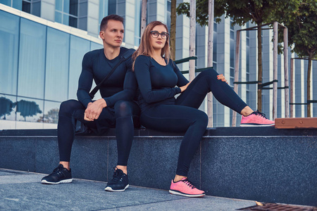健身情侣在运动服, 性感的金发女孩和一个英俊的肌肉男坐在板凳上对