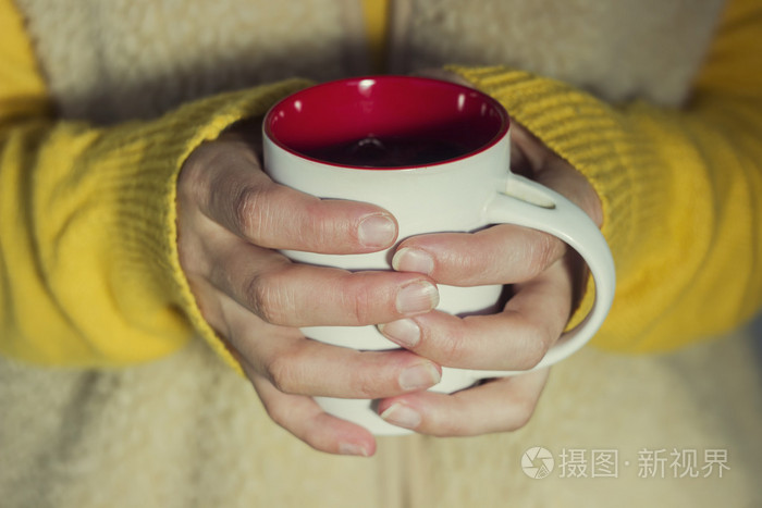 软和模糊概念一个女人握着一杯热的茶温暖着他的手