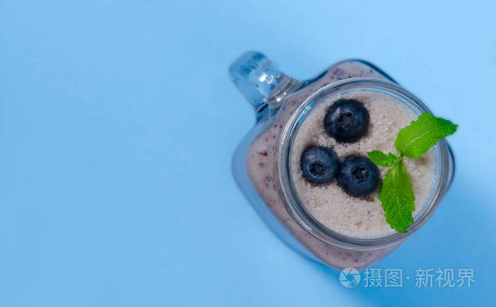 蓝莓冰壶与薄荷在梅森罐子玻璃与浆果和薄荷上面的蓝色桌子上的看法