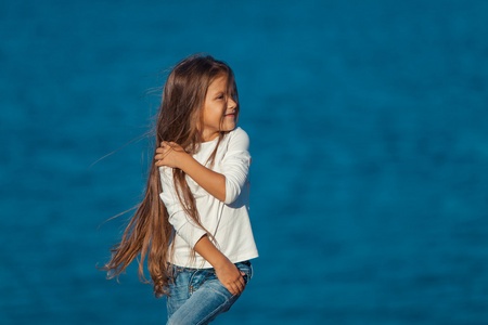 可爱快乐微笑的小女孩在海滩度假。牛仔裤