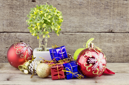 复古外观圣诞装饰品与红球 绿球 红丝带 贝尔 小树上白锅和人造花。老年和脏的木板