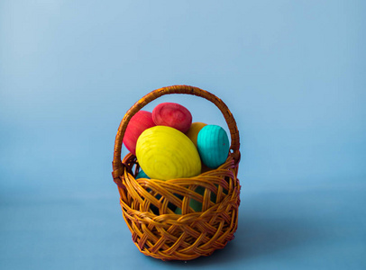 蓝色背景下的柳条篮中的复活节彩蛋