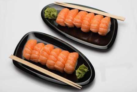 三文鱼寿司 木棍和芥末在豆形窗体的两个黑色陶瓷盘子
